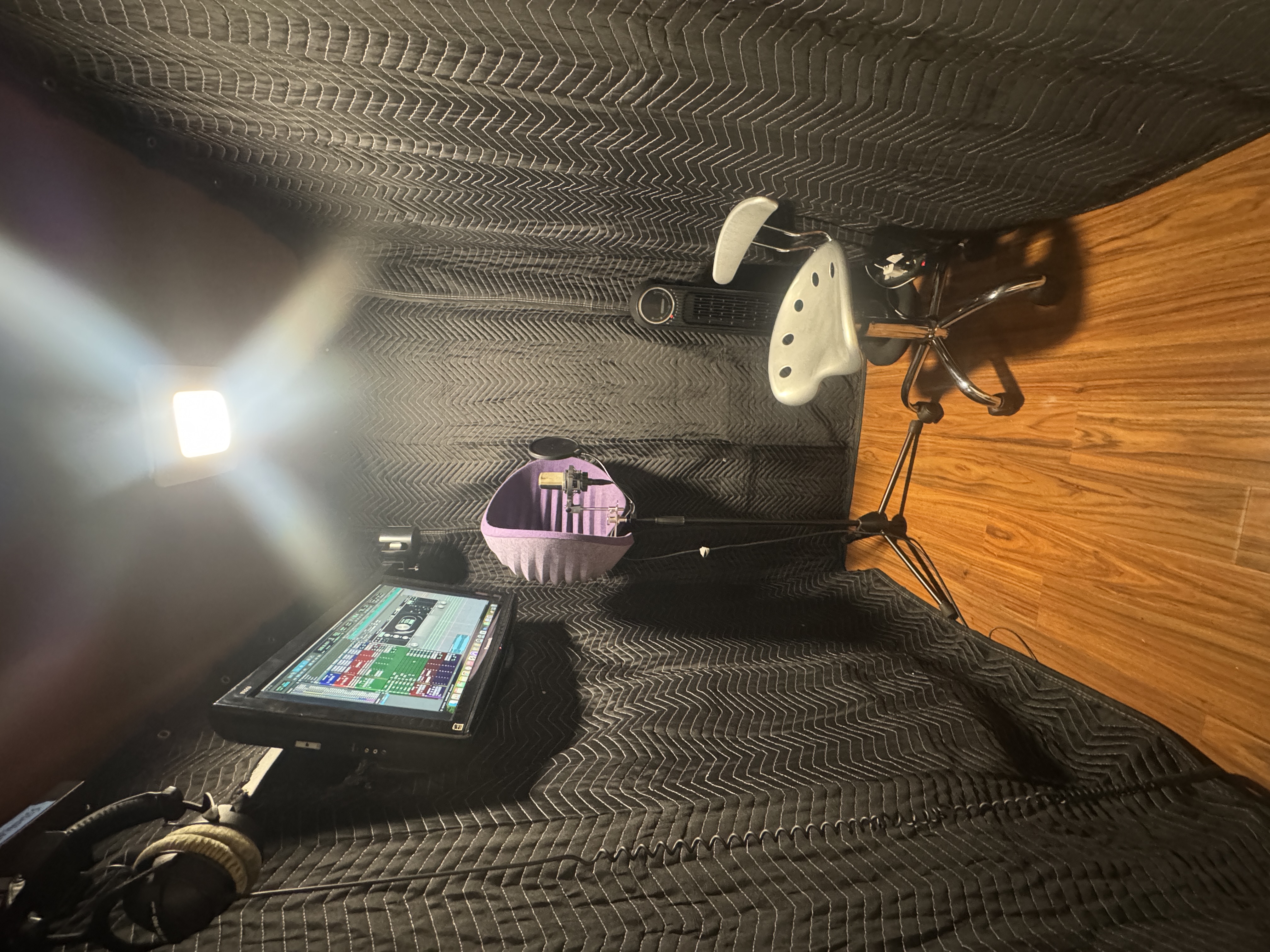 Vocal booth with mic and TV mirroring the session